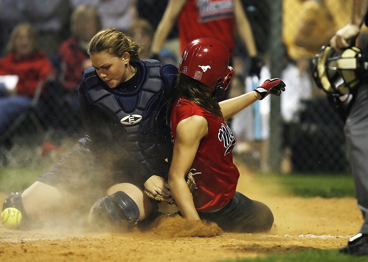 Two softball players, one sliding to home plate
